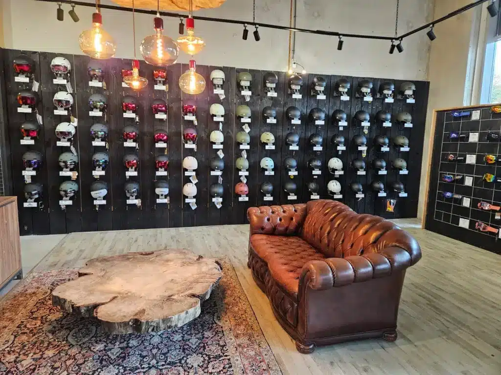De showroom van 2ndride.nl met een wand vol tweedehands skihelmen en skibrillen